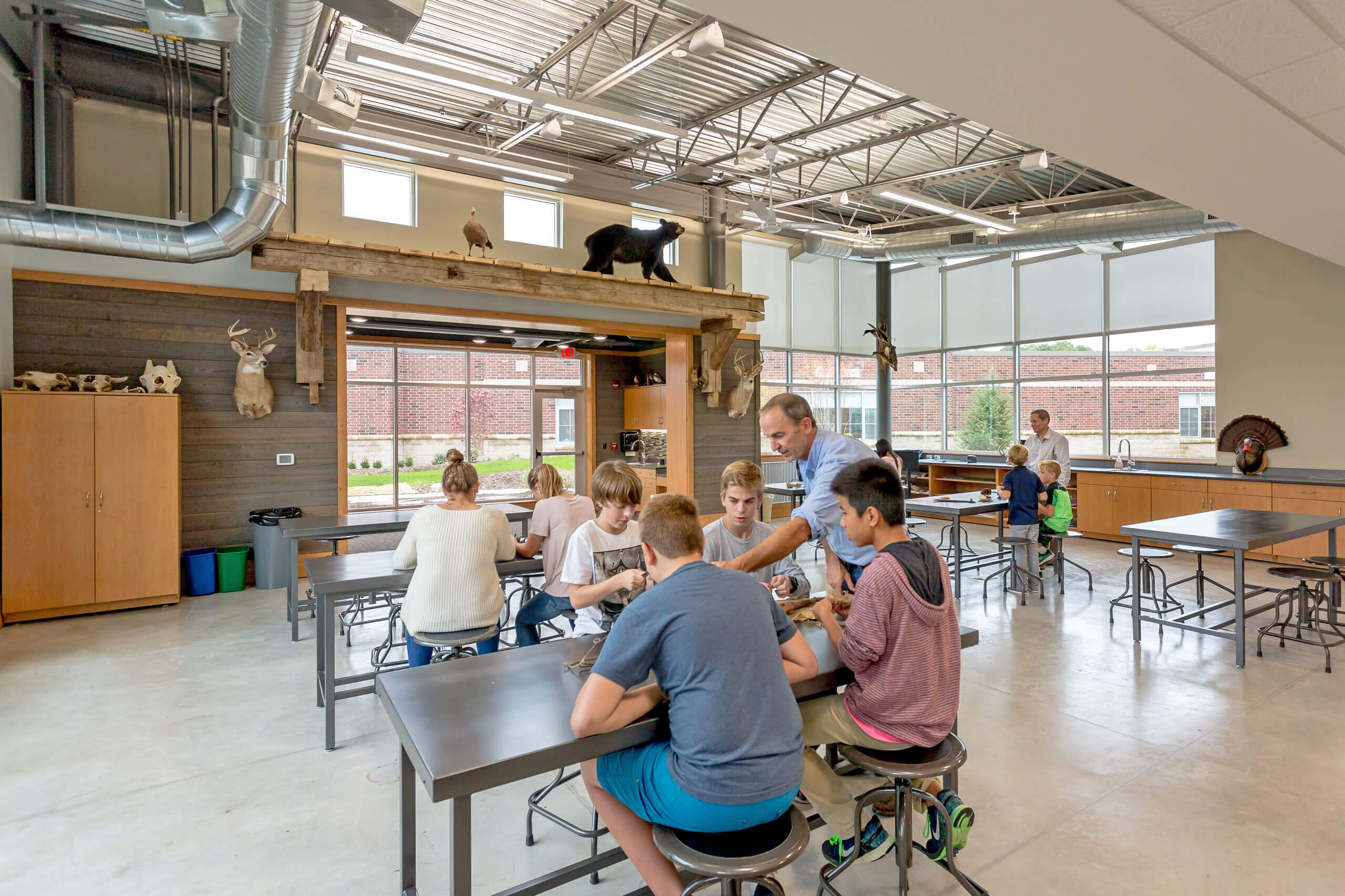 A teacher teaches four boys at a table inside the Integrated Outdoor Education building at Ada Christian School