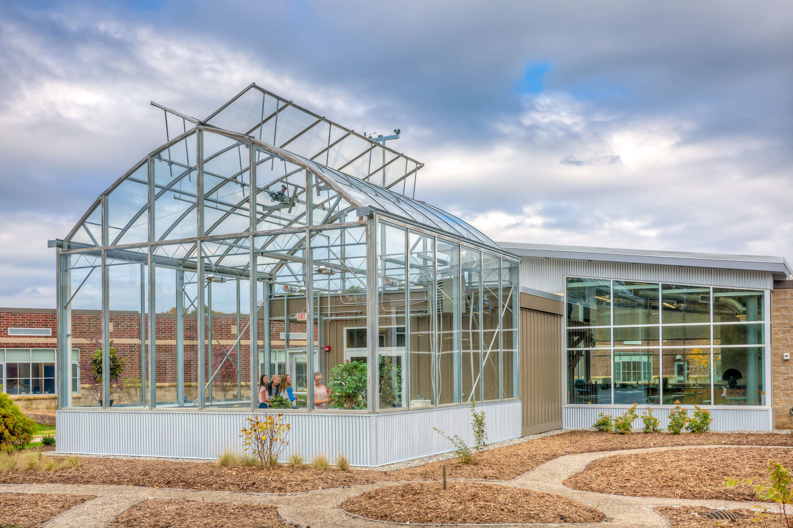 exterior looking in at students inside the greenhouse at the Integrated Outdoor Education building at Ada Christian School