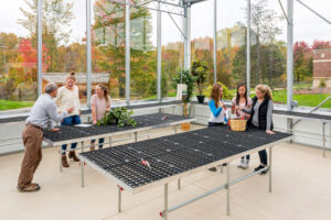 Three adults and three students inside the greenhouse at the Integrated Outdoor Education building at Ada Christian School