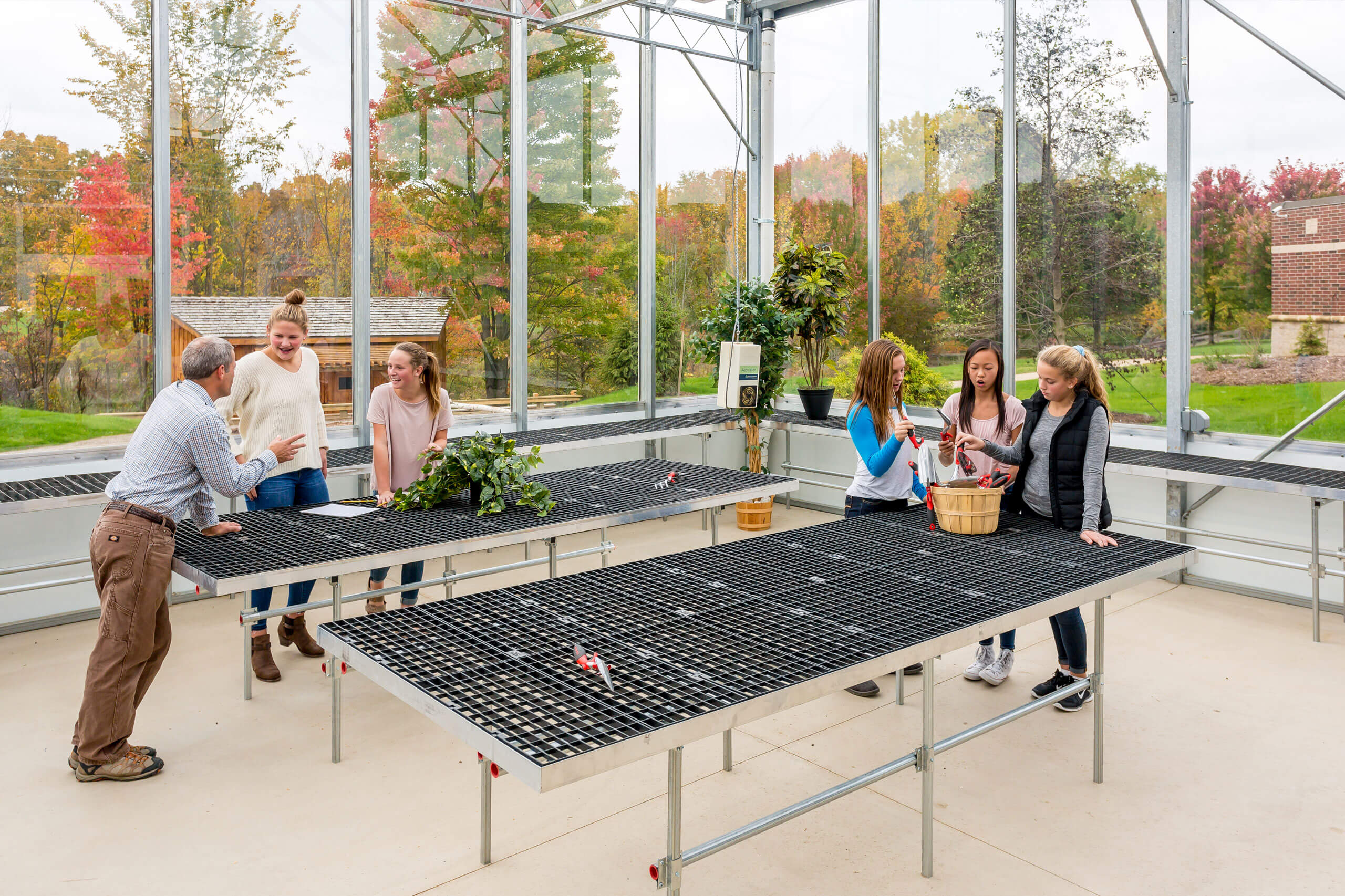 Three adults and three students inside the greenhouse at the Integrated Outdoor Education building at Ada Christian School