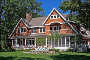 backyard exterior of a shingle-style cottage with brown shingles and white trim