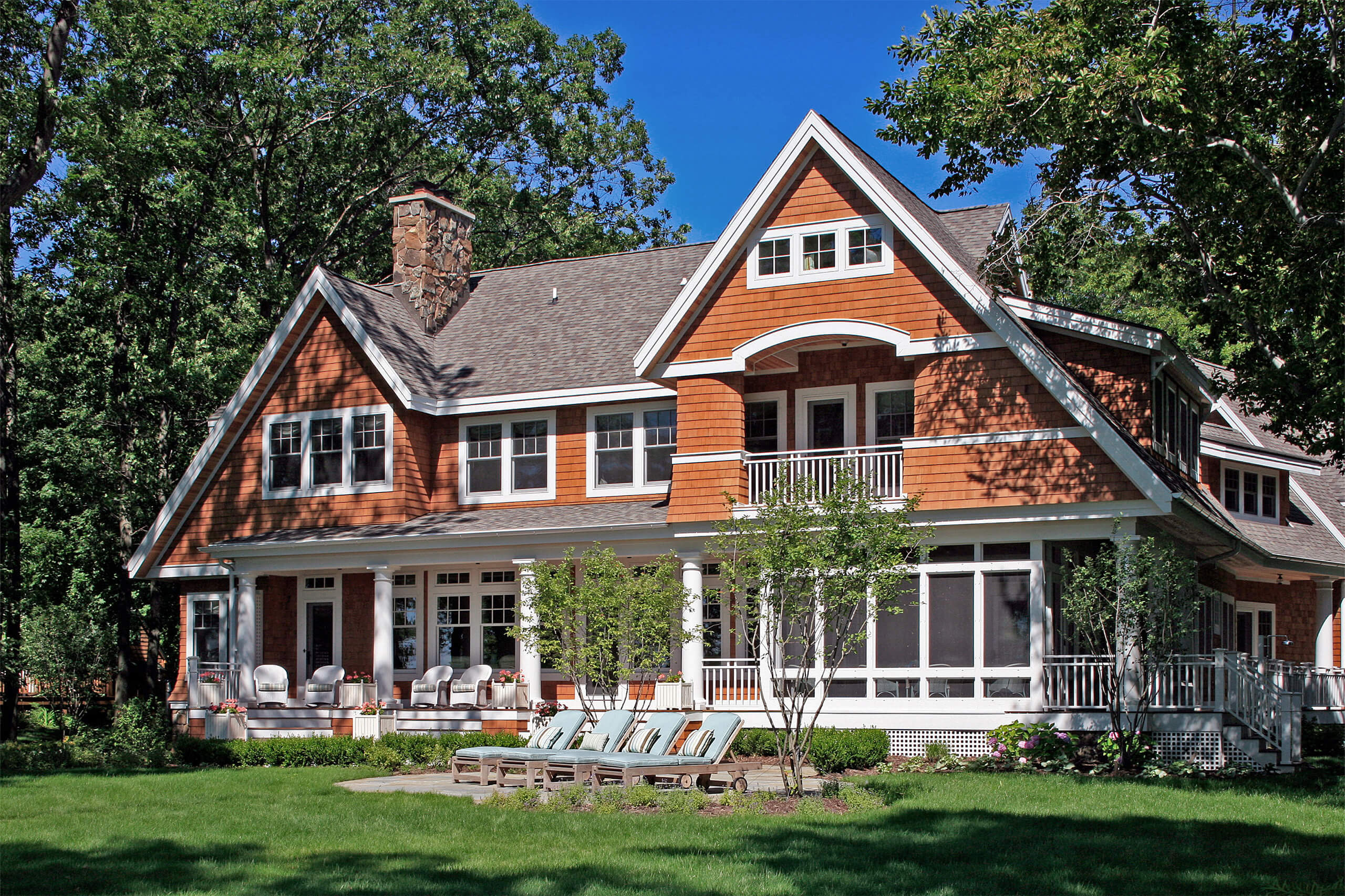 backyard exterior of a shingle-style cottage with brown shingles and white trim