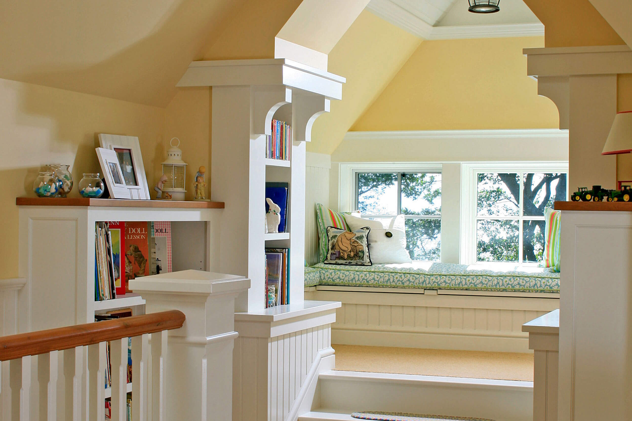 interior lofted nook with cushions on a bench seat with pillows featuring bookshelves