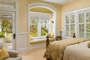 yellow painted bedroom with white trim, window shades and a window seat