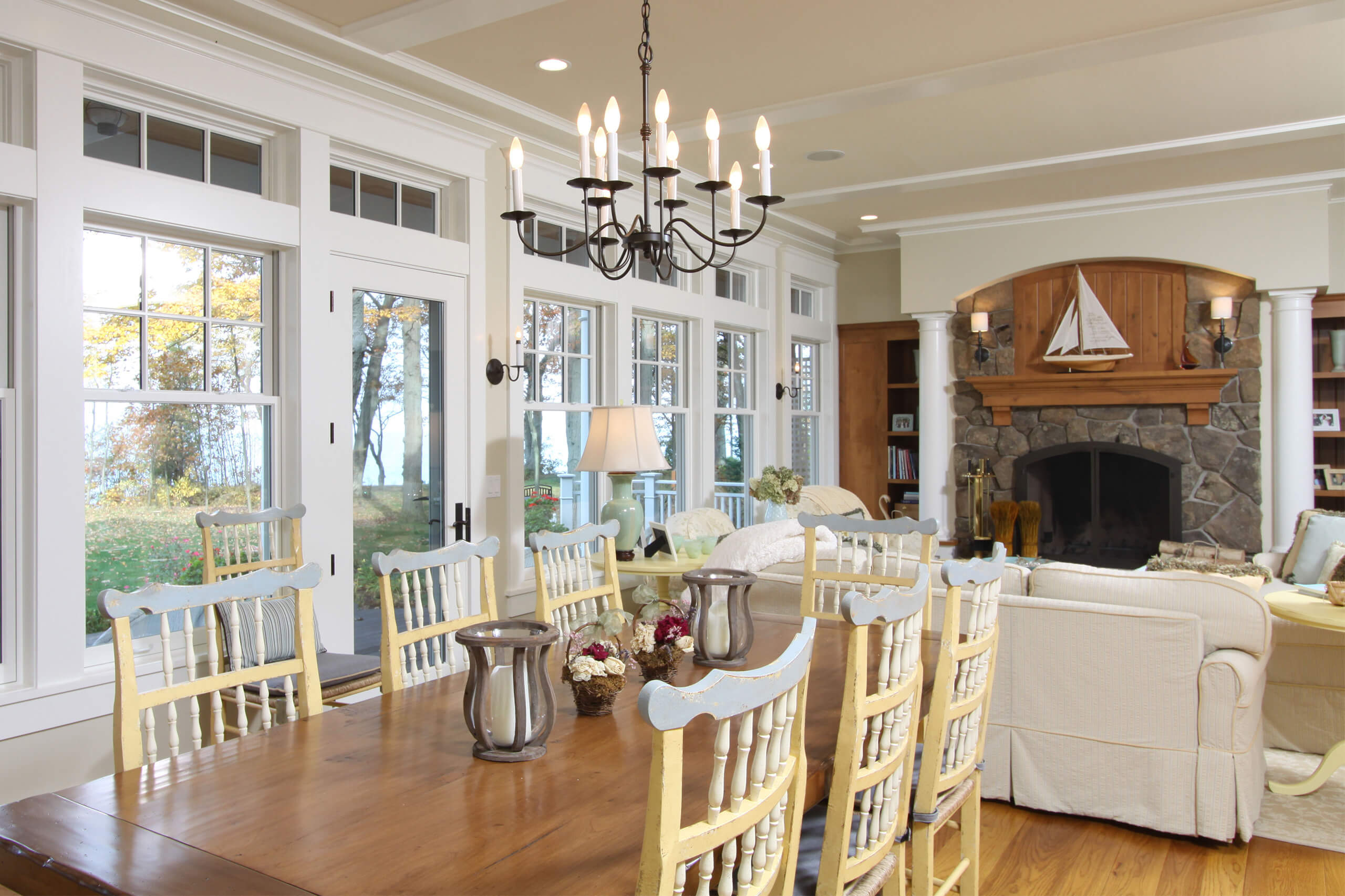 interior of a lake cottage with a dining table, living room area and white windows and doors facing the lake