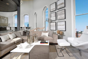 Residential setting inside an urban loft of the living room seating area looking out 5 windows with the blue sky behind