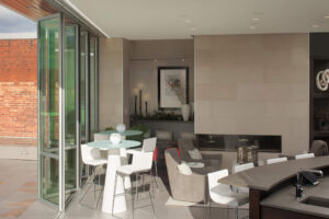 table and chairs, a fireplace and soft seating with a glass accordion door open to a balcony