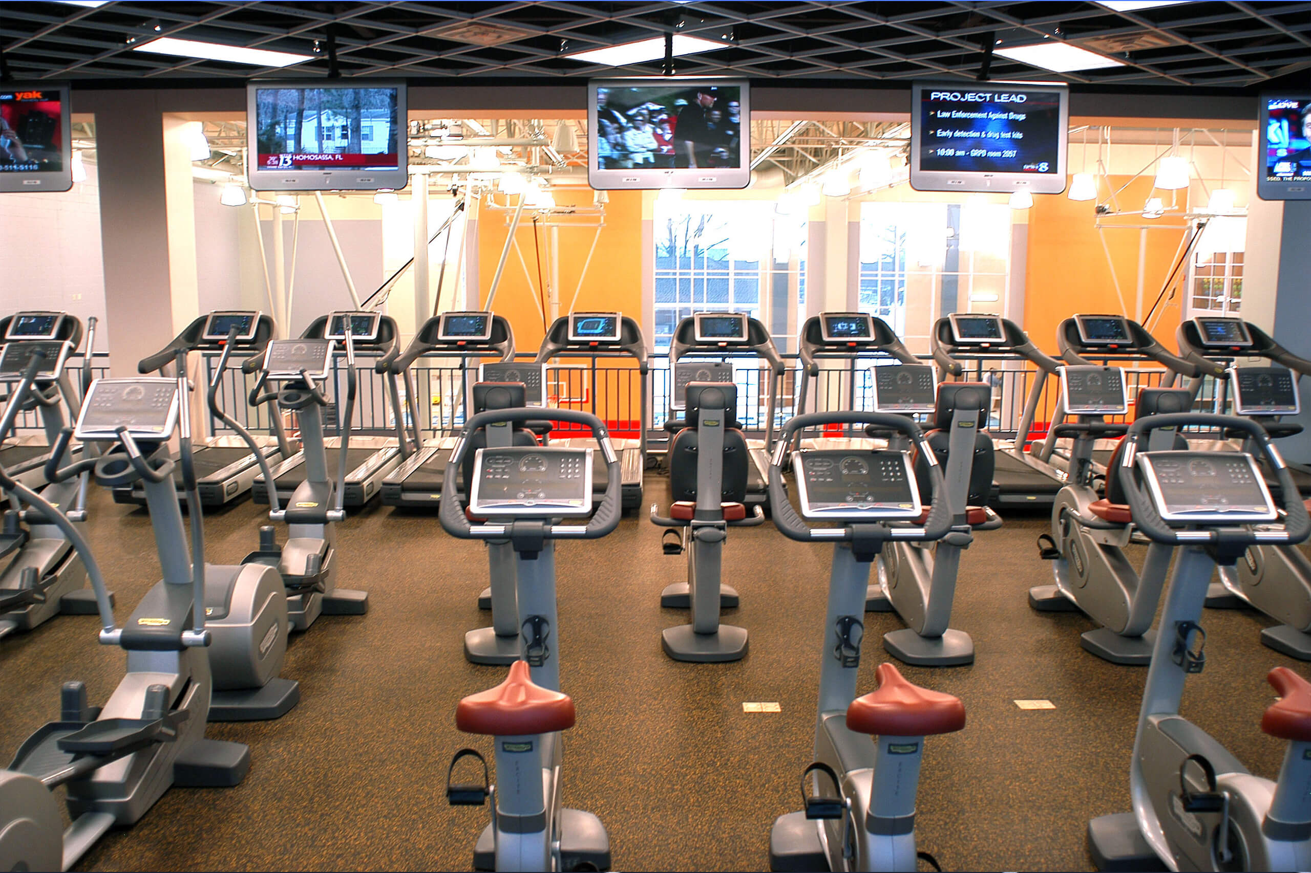 rows of exercise machines overlooking basketball courts on a lower level