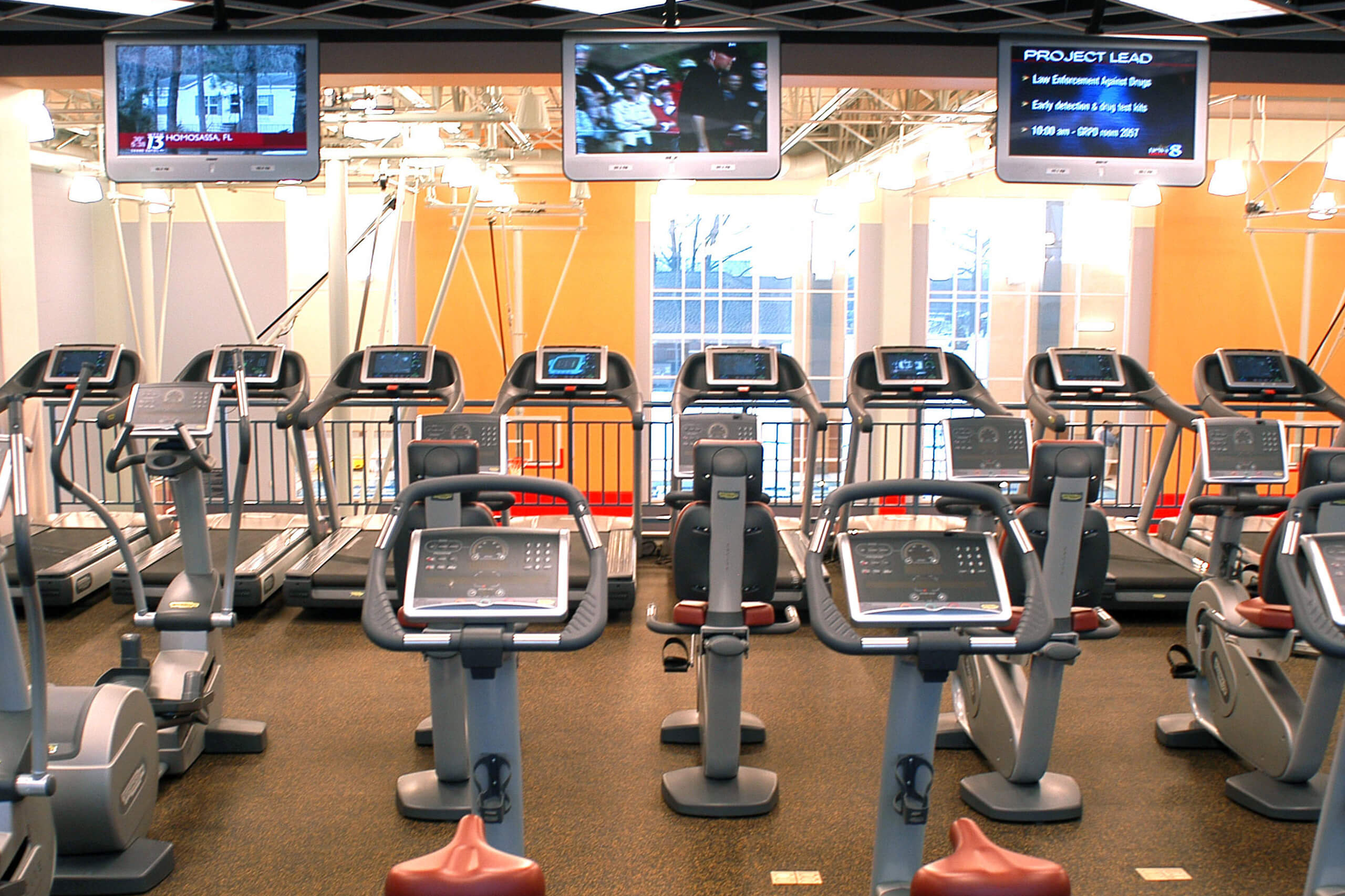 rows of exercise machines overlooking basketball courts on a lower level