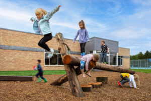 Elementary students outside on playground logs at Bethany Christian Schools.