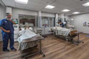 photo of a healthcare room with two patient beds and healthcare staff checking vitals