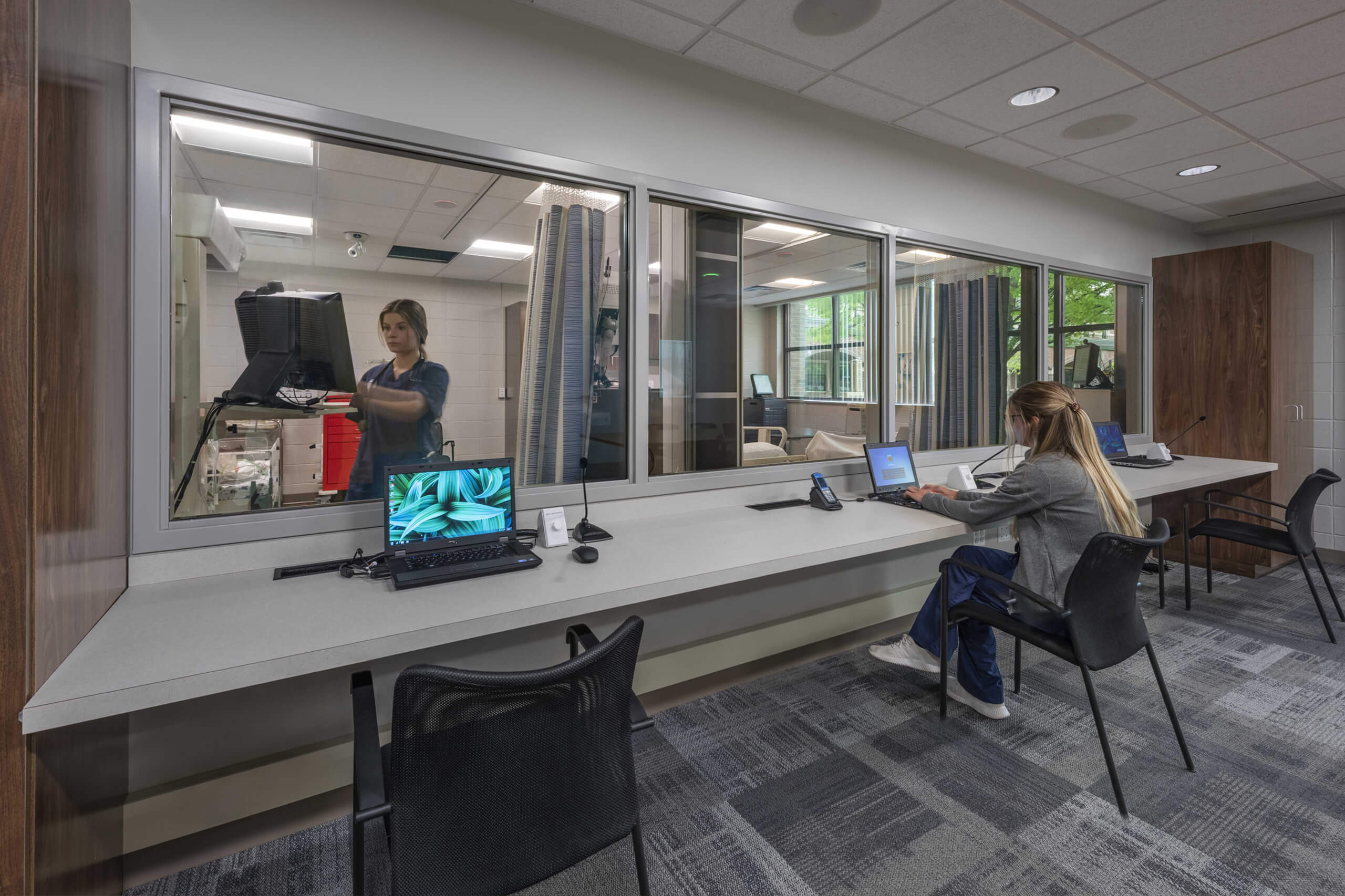 observation rooms with glass windows, nurses on a laptop and with a microphone