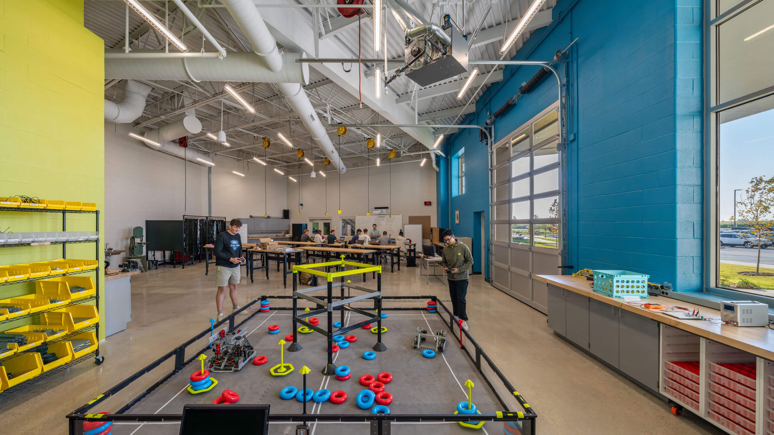 a large room with garage door and robotics area in the foreground