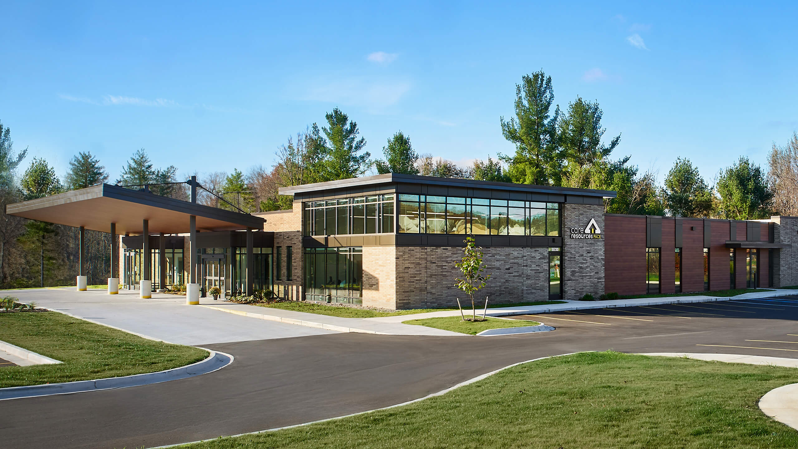 exterior of a building with stone and large windows as well as a canopy-covered drive-up entry