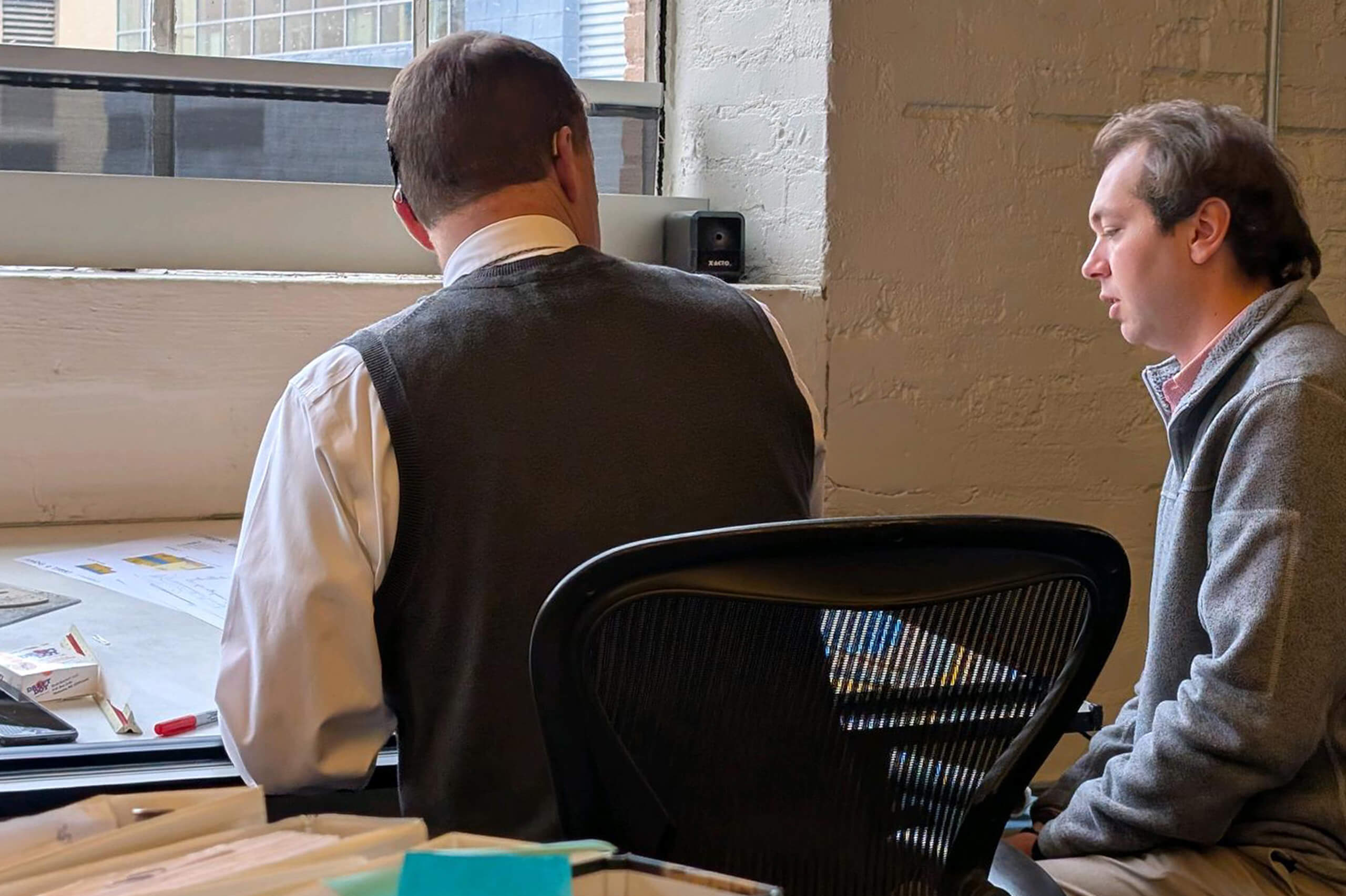 a man mentoring a younger man at a drafting table