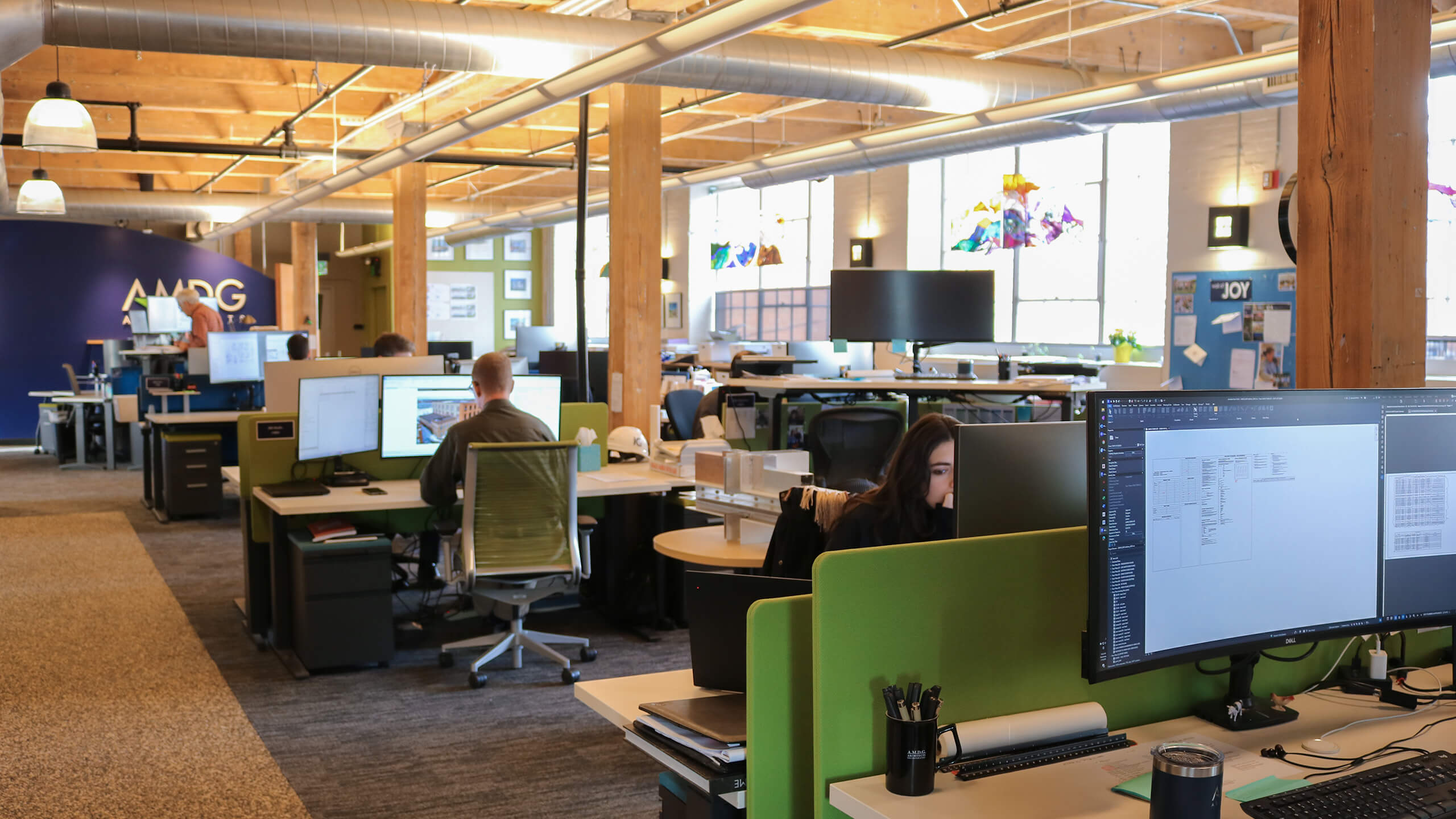 people working in an open room with exposed wooden beams