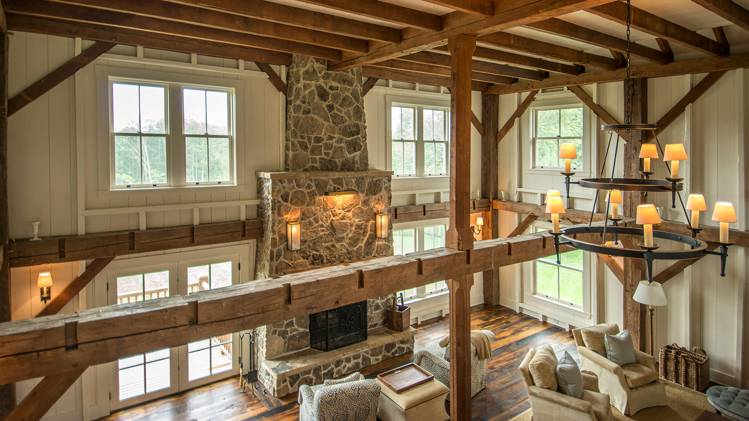 an elevated perspective of a living room with large stone fireplace and exposed rustic wooden beams