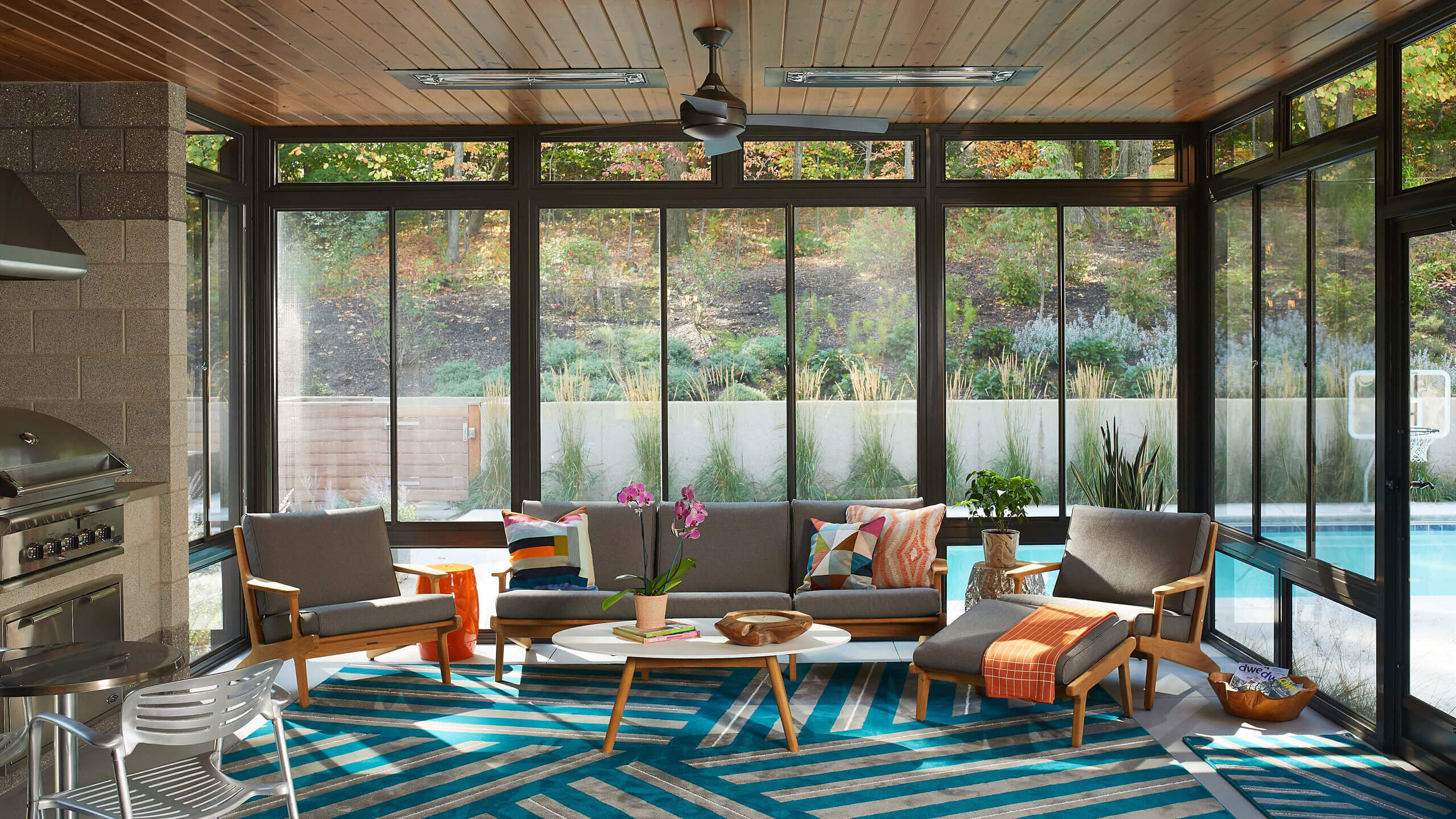 a sunroom with wood paneled ceiling and brightly patterned rug