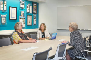 three women talking at a conference table
