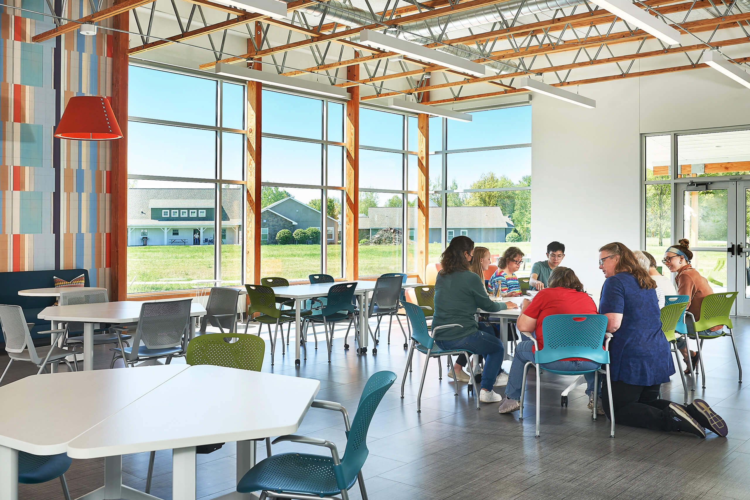 group of people sitting at a table in large multipurpose room with big windows letting in natural light
