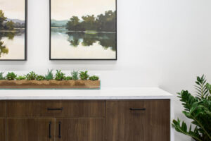 detail of paintings hanging over a waterfall edge counter with wooden drawer and cabinet fronts