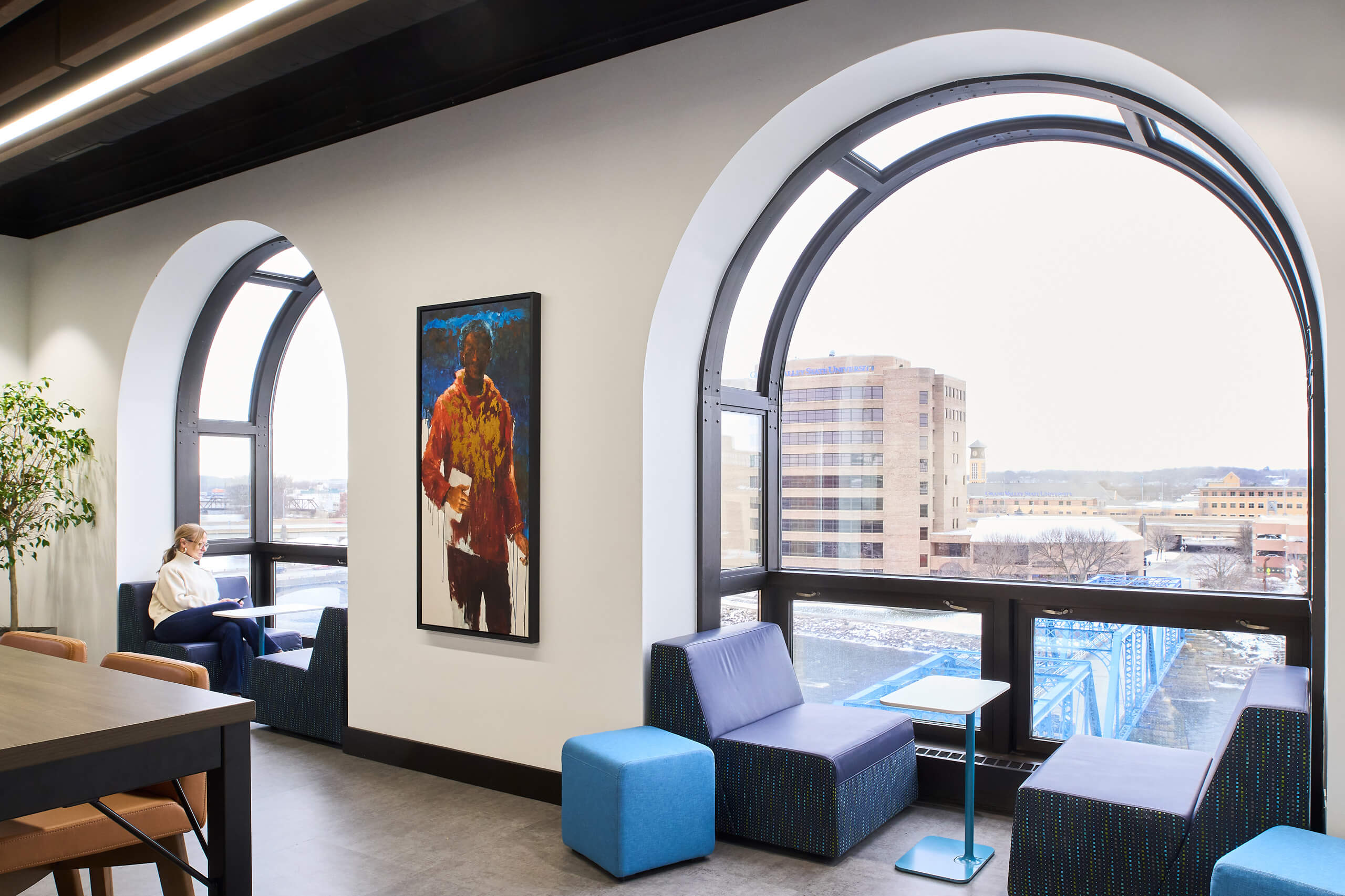 arched windows with cushioned seating within nooks that overlook the river and a blue bridge