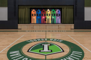 colorful row house backdrop on performance stage along one edge of a gymnasium