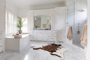bright and spacious bathroom with built-in tub, walk-in shower, and cowskin rug covering a marble floor
