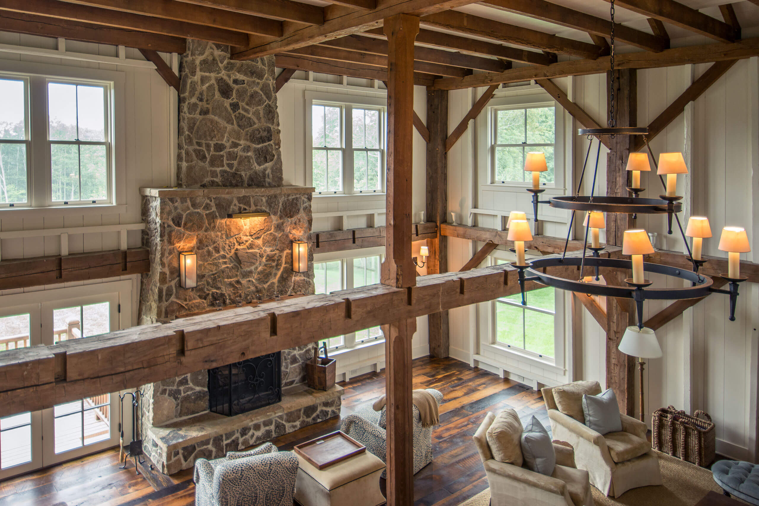 high perspective of a rustic style living room with exposed wooden beams and stone fireplace